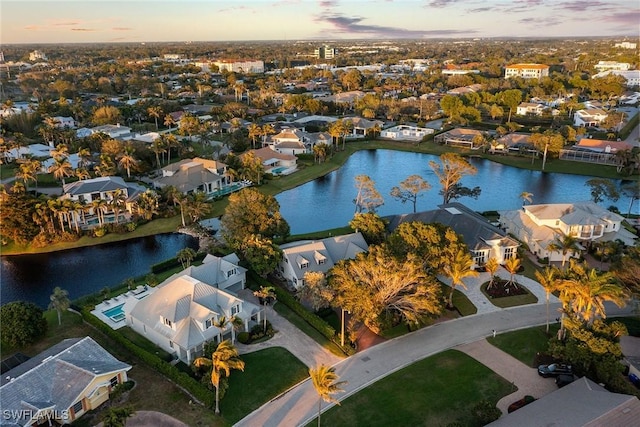 aerial view at dusk featuring a residential view and a water view