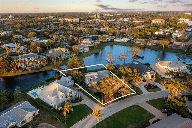 aerial view at dusk featuring a residential view and a water view