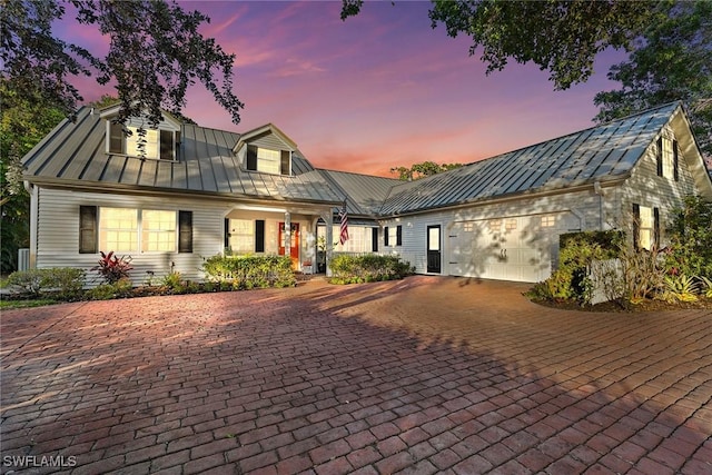 view of front facade with a standing seam roof, decorative driveway, a garage, and metal roof