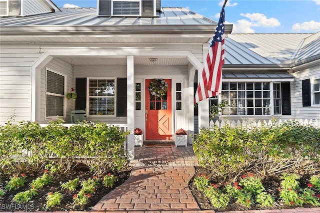 doorway to property with covered porch, metal roof, and a standing seam roof