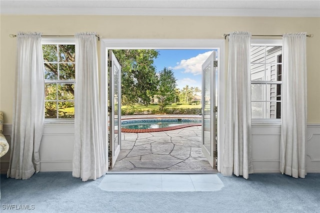 doorway featuring crown molding and carpet floors