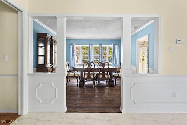 dining area with decorative columns, visible vents, marble finish floor, and a textured ceiling