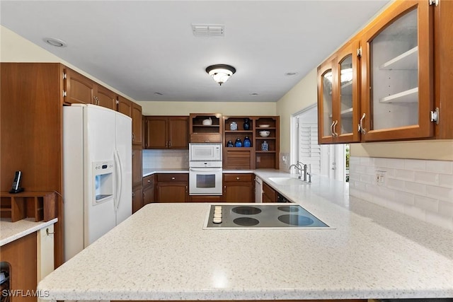 kitchen with visible vents, open shelves, a peninsula, white appliances, and a sink