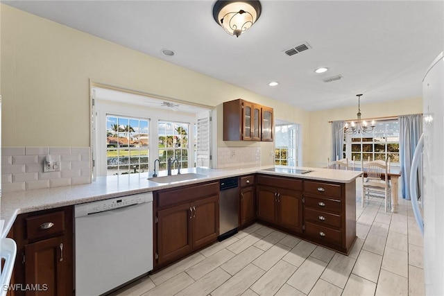 kitchen featuring visible vents, a peninsula, a sink, dishwasher, and black electric cooktop