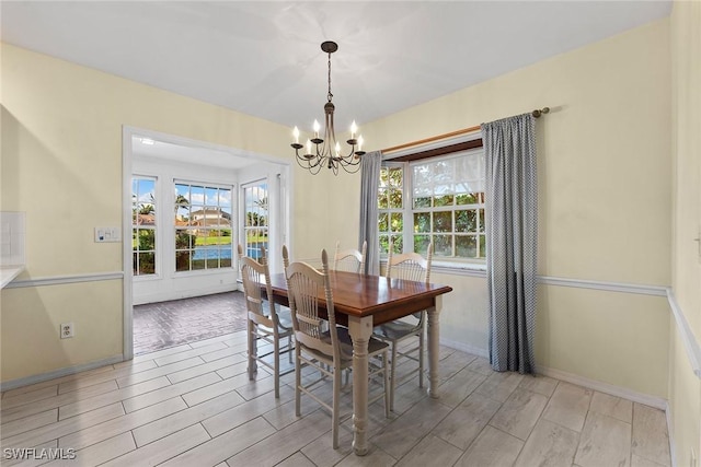 dining area with wood finish floors, baseboards, and a notable chandelier