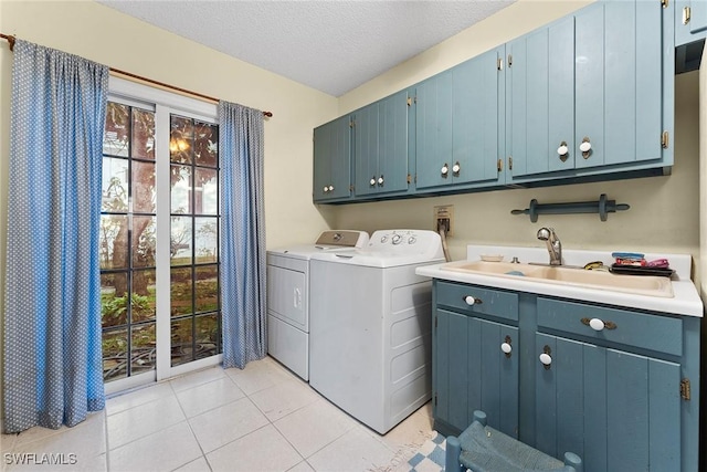 laundry room with washer and dryer, a sink, a textured ceiling, cabinet space, and light tile patterned floors