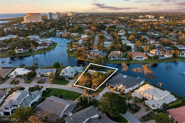 aerial view at dusk with a residential view and a water view