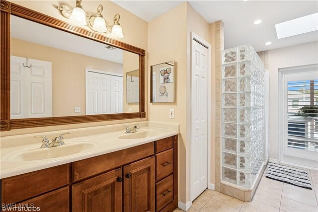 full bathroom featuring tile patterned floors, a skylight, tiled shower, and a sink