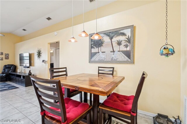 dining room with light tile patterned floors, visible vents, baseboards, and vaulted ceiling