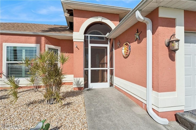 doorway to property with stucco siding and an attached garage