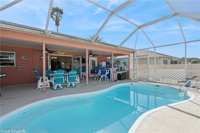 view of pool featuring fence, glass enclosure, a fenced in pool, ceiling fan, and a patio area