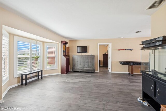 living area with visible vents, baseboards, and wood finished floors