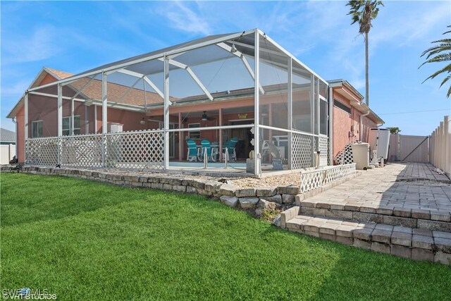 rear view of property with a patio area, glass enclosure, and a yard