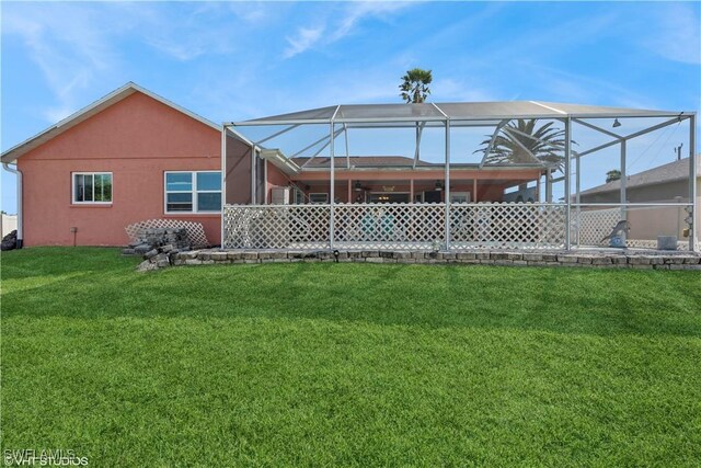 rear view of property with glass enclosure, a yard, and stucco siding