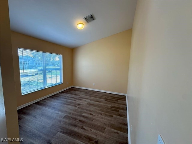 unfurnished room featuring wood finished floors, visible vents, and baseboards