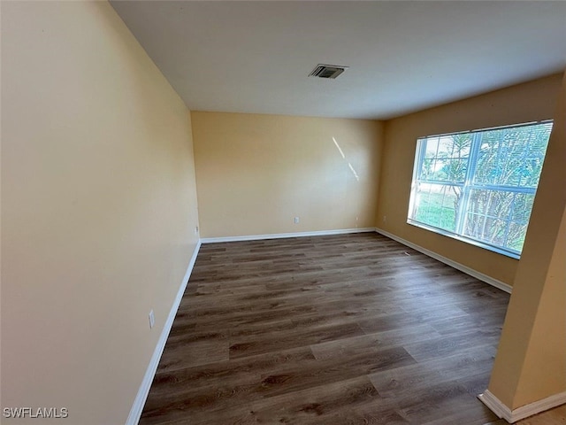 unfurnished room featuring visible vents, baseboards, and wood finished floors