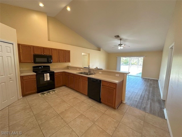 kitchen featuring a peninsula, a sink, black appliances, light countertops, and brown cabinets