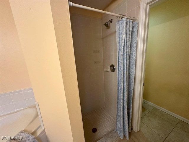 bathroom featuring tile patterned flooring, a stall shower, and baseboards