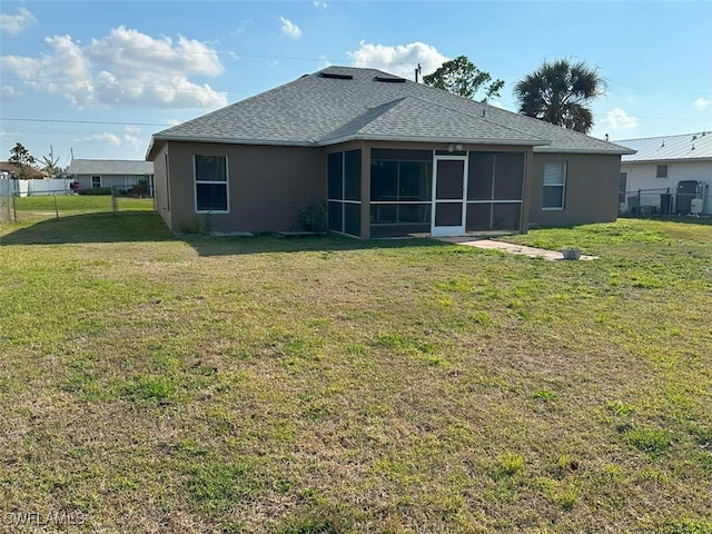 rear view of property featuring a yard, fence, a sunroom, and a shingled roof