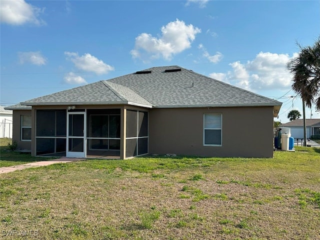 rear view of house with stucco siding, a shingled roof, a yard, and a sunroom