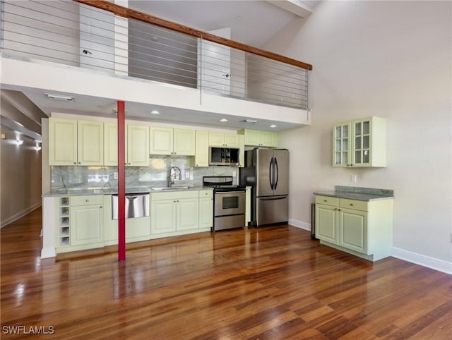 kitchen featuring dark wood-type flooring, high vaulted ceiling, a sink, backsplash, and stainless steel appliances