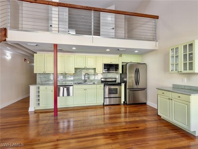 kitchen featuring dark wood-type flooring, baseboards, decorative backsplash, stainless steel appliances, and a sink