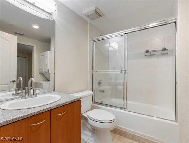 bathroom with tile patterned flooring, visible vents, toilet, combined bath / shower with glass door, and stacked washer / drying machine