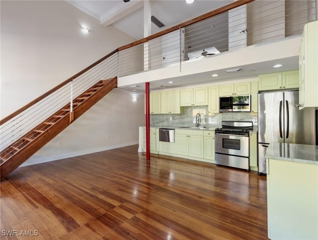 kitchen with dark wood-style floors, a high ceiling, ceiling fan, a sink, and appliances with stainless steel finishes