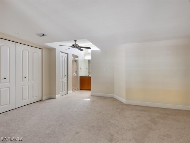 interior space featuring visible vents, light colored carpet, a ceiling fan, and baseboards