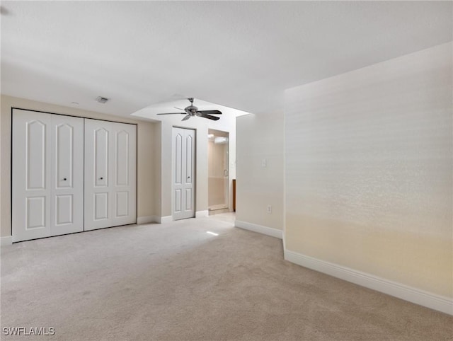 unfurnished bedroom with light colored carpet, connected bathroom, baseboards, and ceiling fan