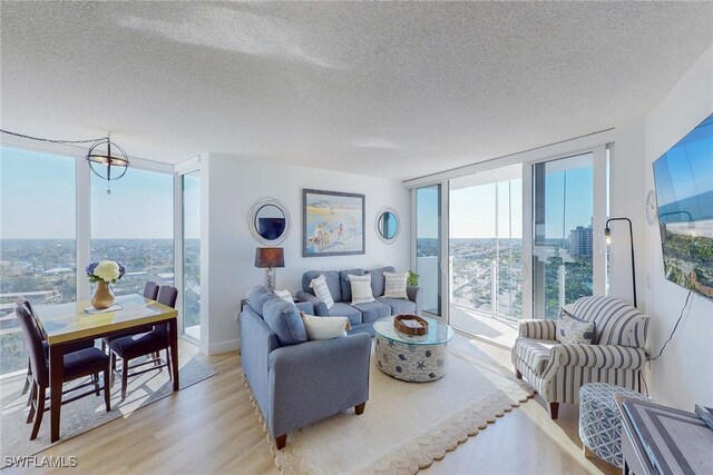 living room featuring light wood-type flooring, a textured ceiling, and floor to ceiling windows