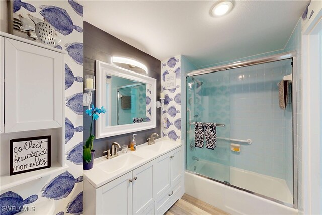 bathroom featuring double vanity, combined bath / shower with glass door, and a sink