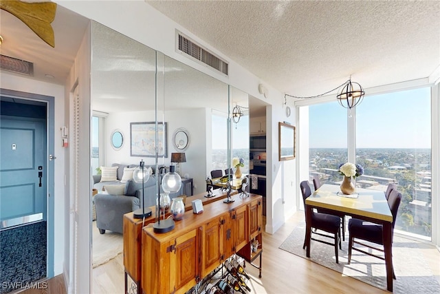 dining room featuring light wood-style floors, a healthy amount of sunlight, visible vents, and a textured ceiling