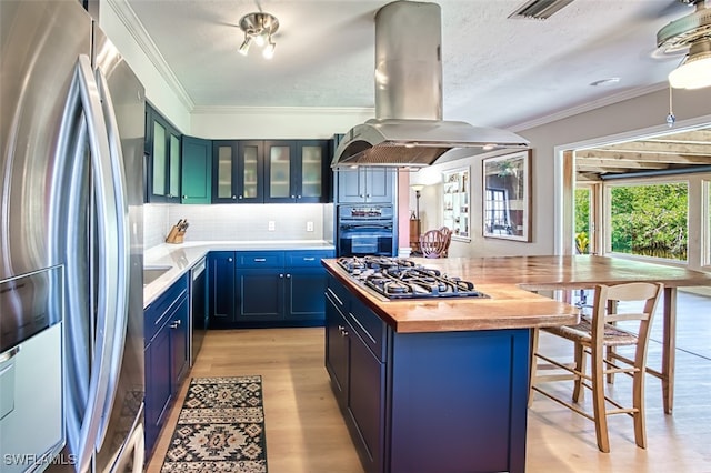 kitchen with wooden counters, blue cabinetry, island exhaust hood, stainless steel appliances, and crown molding