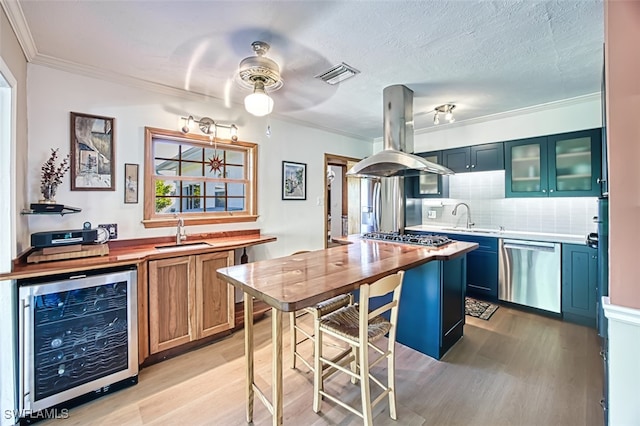 kitchen featuring beverage cooler, visible vents, island exhaust hood, a sink, and appliances with stainless steel finishes