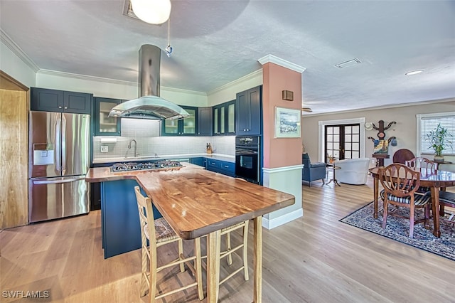 kitchen featuring island range hood, blue cabinetry, oven, stainless steel fridge, and butcher block counters