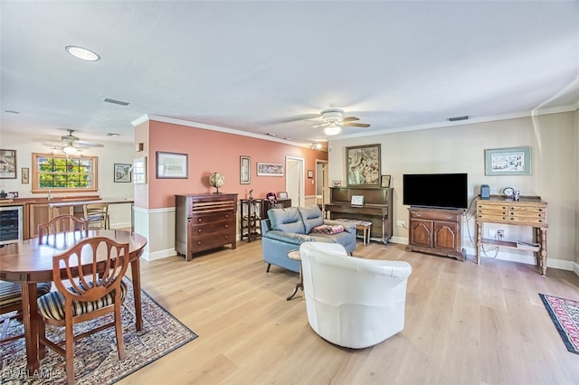 living room with ceiling fan, baseboards, light wood-style floors, and ornamental molding