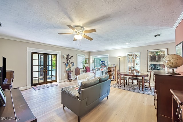 living room featuring french doors, a textured ceiling, visible vents, and light wood-style flooring