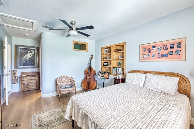 bedroom featuring attic access, a ceiling fan, baseboards, and wood finished floors