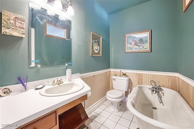 full bath with vanity, a freestanding bath, tile patterned flooring, wainscoting, and toilet