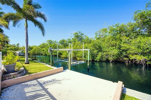 dock area with boat lift, a yard, and a water view