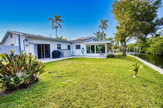 back of house with stucco siding, a lawn, a patio, and fence