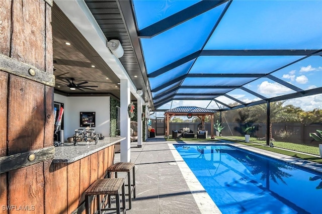 view of swimming pool with outdoor dry bar, a patio, glass enclosure, a fenced in pool, and ceiling fan