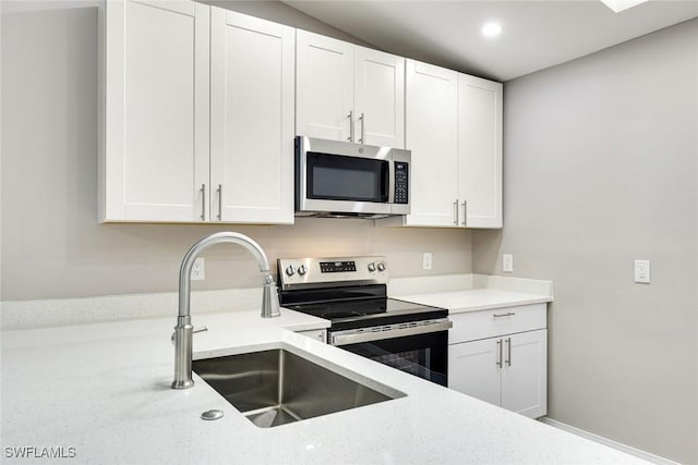 kitchen featuring recessed lighting, white cabinets, stainless steel appliances, and a sink