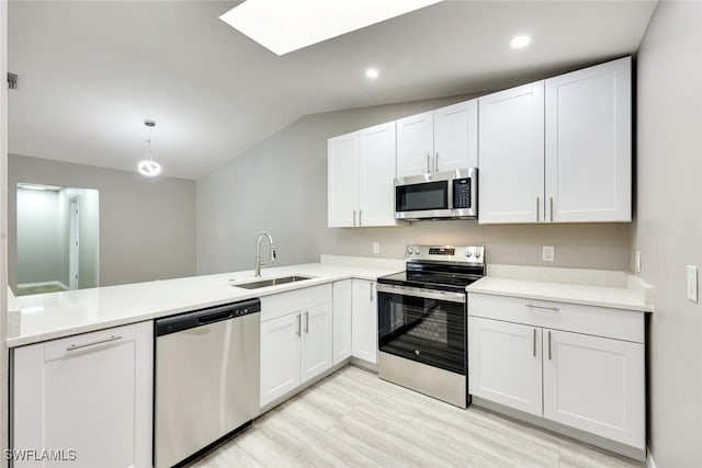 kitchen featuring a sink, stainless steel appliances, a peninsula, light countertops, and vaulted ceiling