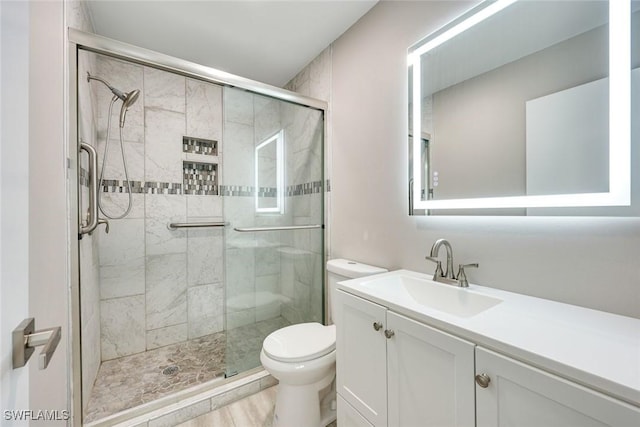 full bathroom featuring vanity, a shower stall, and toilet