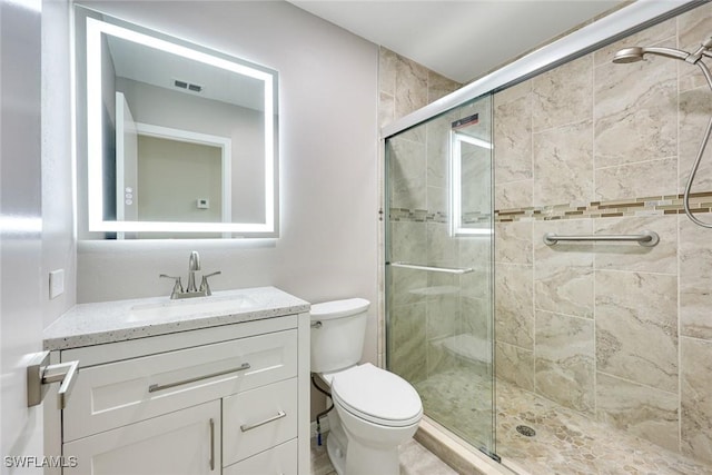 bathroom with visible vents, vanity, toilet, and a shower stall