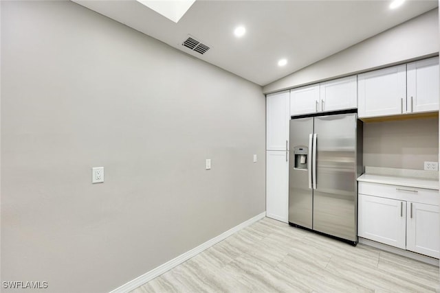 kitchen featuring white cabinetry, light countertops, baseboards, and stainless steel fridge with ice dispenser