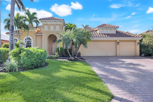 mediterranean / spanish home with a front lawn, decorative driveway, a tile roof, and stucco siding