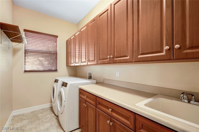 clothes washing area featuring washer and clothes dryer, a sink, cabinet space, light tile patterned floors, and baseboards